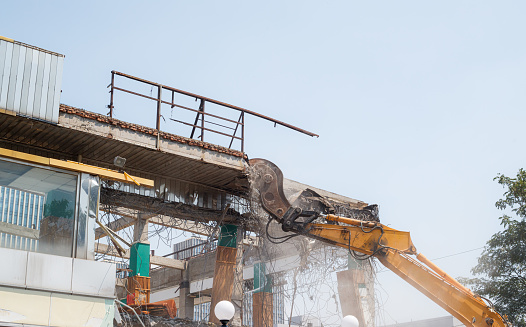 A young Caucasian male construction worker is taking a break to wipe the sweat from his forehead.