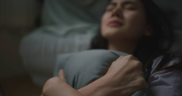 istock Depressed young Asian woman hugging pillow 1703259146