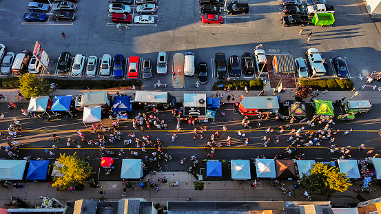 Penn Avenue alive with Fall Festivities: crowded street hosting street party with busy cafes and food trucks in West Reading, Pennsylvania, USA. Drone view