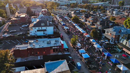 Sunny street party celebrations during Fall Festival. Cafes and food stalls line crowded street in West Reading, pennsylvania, USA. Drone view.