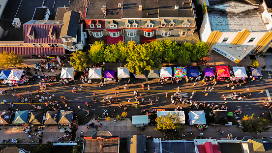 Small town party in Fall: autumnal Street Food Festival with busy food trucks lining lively street. Aerial top view
