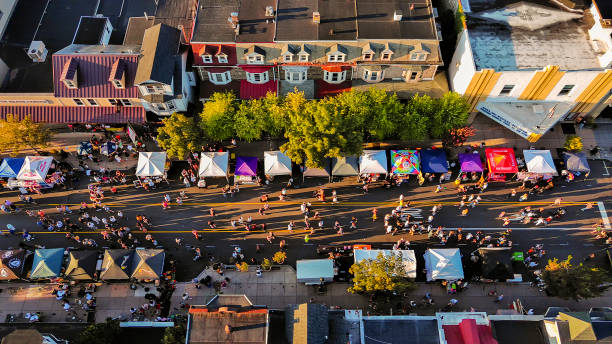 Small town party in Fall: autumnal Street Food Festival with busy food trucks lining lively street. Aerial top view Food trucks and cafes during Autumn Street Festival on crowded Penn Avenue in West Reading, Pennsylvania. USA. Drone view small town america stock pictures, royalty-free photos & images