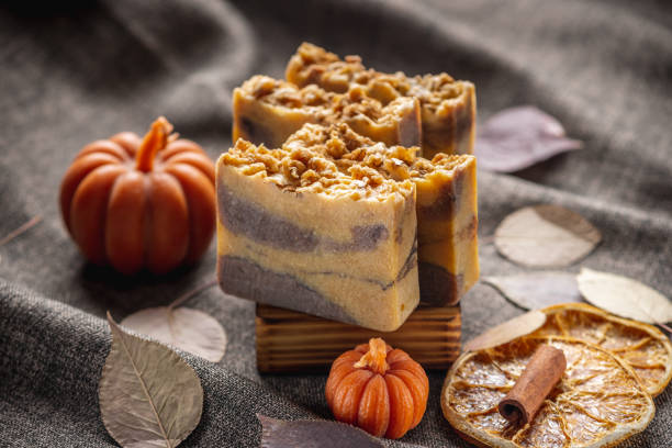 istock Handmade fragrant natural soap and pumpkin shaped candles on a dark background with yellow dry leaves to create a cozy atmosphere . Beautiful autumn postcard 1703299846