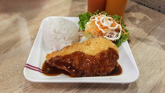 Crispy Katsu chicken with sauce, rice and cabbage on the square white plate