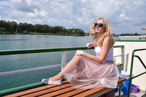 Blond mature woman sitting on a bench of the ship deck