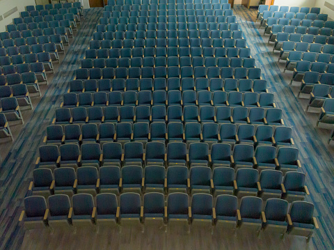 Overhead view of empty gray and blue theater, auditorium seats, chairs.