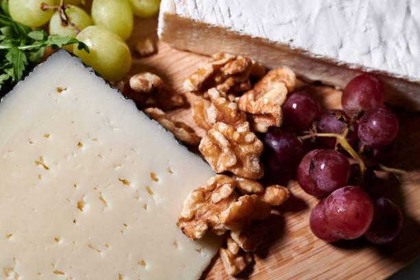 A cutting board with a selection of grapes and cheese on display