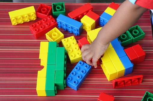 kids hand playing with colorful building blocks, toddler development concept, joy, life