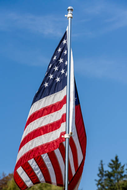 istock American flag over blue sky background, closeup 1703421242