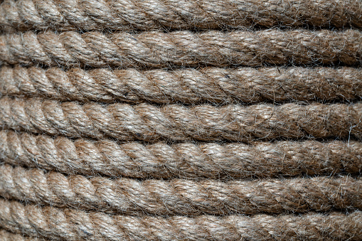 Natural jute hemp rope rolled into a coil, close up. Brown spool of linen rope texture on the background