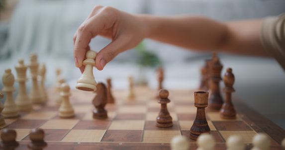 selective focus,  Close up hand of young woman moving pieces on chess board during competition with friend, they are have fun during challenge in chess game together
