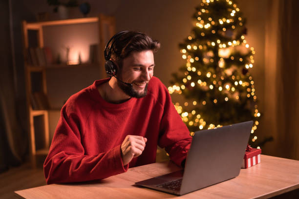 istock Young caucasian man call center agent working sitting by christmas tree at home looking at laptop screen 1703451869