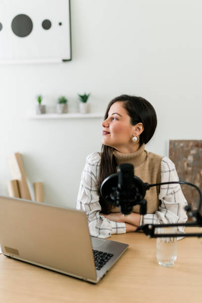 istock Young smiling woman recording podcast and doing live streaming using microphone and headphones in recording studio 1703468152