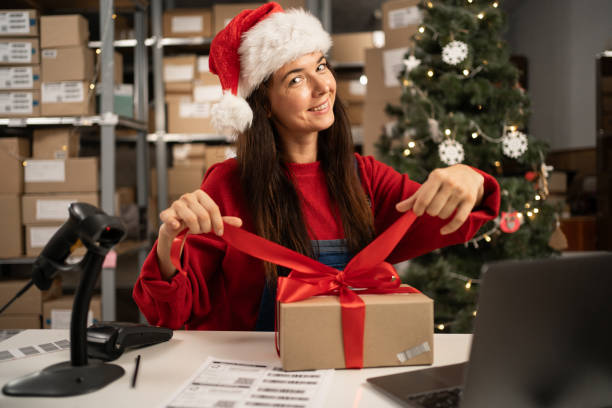 istock Santa Claus packing present box wrapping gift with red ribbon preparing post shipping delivery parcel. Christmas shipping delivery 1703480692