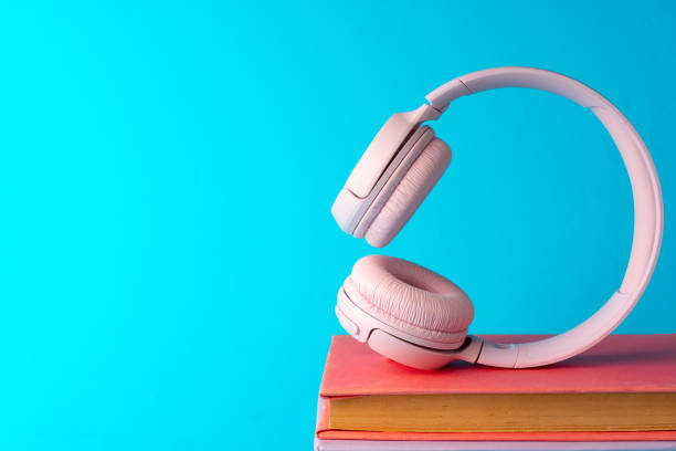 istock Pink headphones on a book on blue background 1703526213