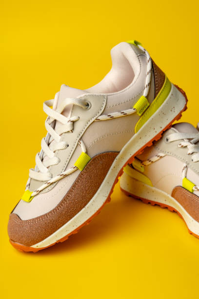 istock Beige sport running shoes on yellow studio background 1703537027