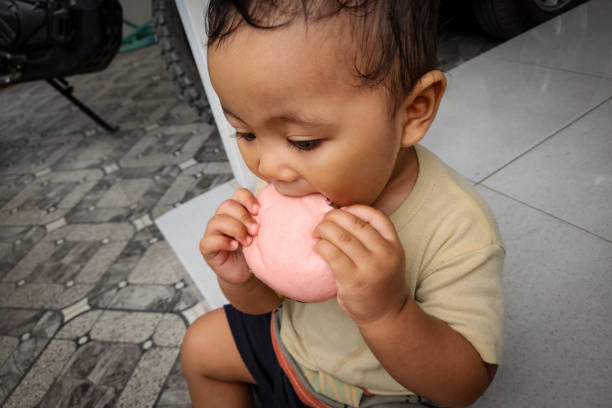 the baby was sitting while biting a steam bun