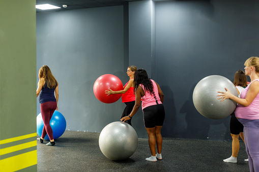A group of pregnant women use pilates ball in the gym.