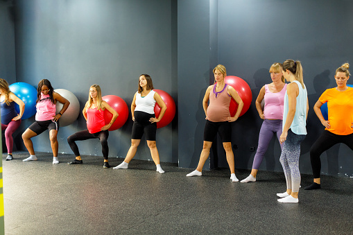 Group of pregnant women practicing pilates. They are working wall squats.