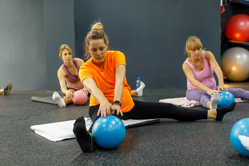 Pregnant women practice with small pilates balls.