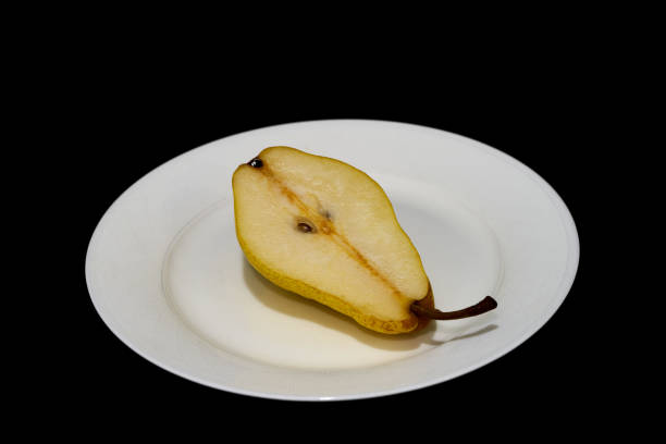 part of a yellow pear lies on a black background.