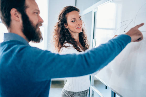 istock Young colleagues drawing a business plan on whiteboard in the office. 1703627851