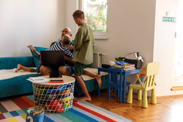 istock Two boys climbing and disrupting their father while he is working from home 1703637229
