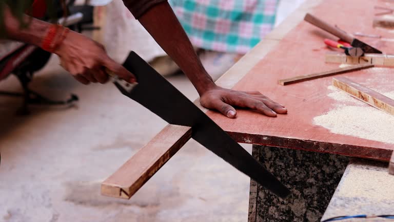 Carpenter cutting wood with hand saw