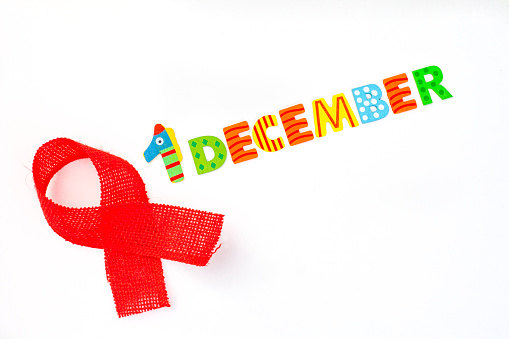 1 December written in colorful lettering on white background with red awareness ribbon