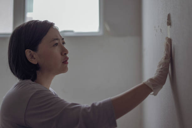 istock Woman looks at broken wallpaper 1703681277