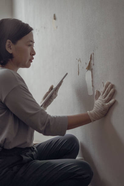 istock Woman looks at broken wallpaper 1703681595