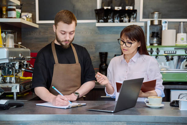 istock Team male and woman talking, working, using laptop, coffee shop 1703698372