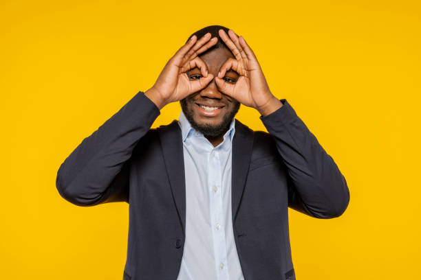 istock Young african businessman holding fingers forming binoculars 1703700975