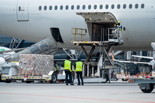 Workers are loading  cargo logistic containers to an airplane. Air transport shipment prepare for loading to modern freighter jet aircraft at the airport.