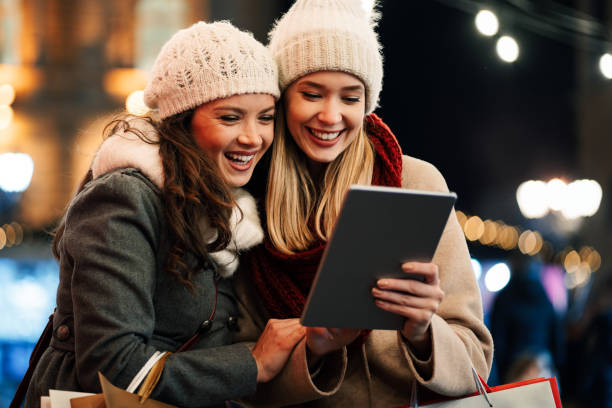 women friends enjoy the night in shopping at christmas. sale, people digital tablet concept - ipad shopping gift retail imagens e fotografias de stock