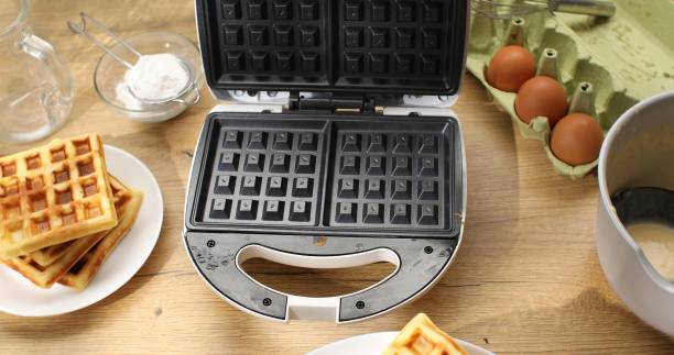 istock Cooked waffles and electric waffle iron. 1703711452
