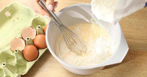 istock Flour is added to a bowl with beaten eggs. 1703711478