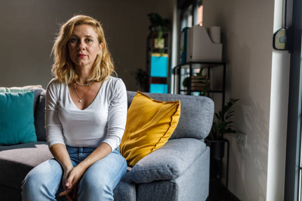 istock Woman sitting on the sofa, looking at camera and smiling 1703729123