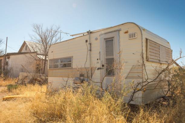 istock Aged trailer situated in a rural area, surrounded by an expansive field. 1703730725