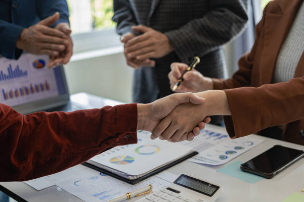istock Happy businessmen shaking hands making proposals in meeting on office table with graph charts Holding financial documents. Proposal contract. Manager and customer shaking hands. Close-up pictures 1703746368