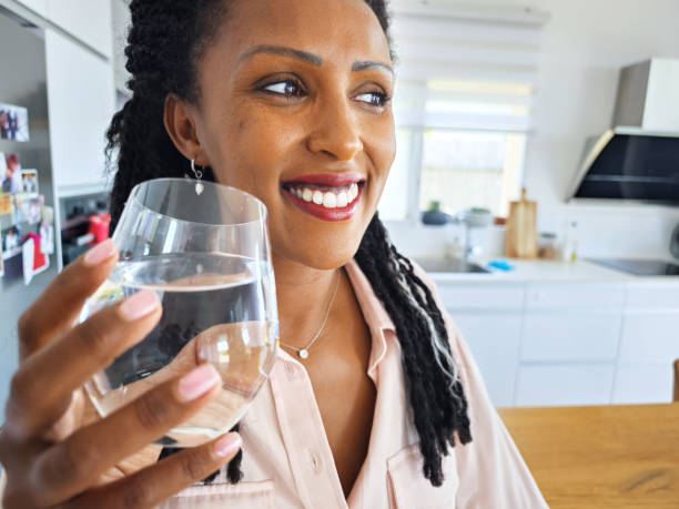 istock Happy woman drinking water in the kitchen. 1703755294