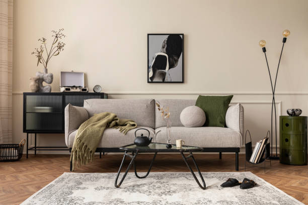 istock Creative composition of living room interior with mock up poster frame, gray sofa, black coffee table, patterned rug, plants in flowerpots, slippers and personal accessories. Home decor. Template. 1703793214