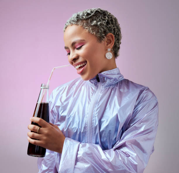 istock Smile, cola and woman with soda in studio drinking to hydrate and refresh with a cool beverage and straw in a bottle. Happy and young girl in fancy modern clothes enjoys a cold fizzy and tasty liquid 1703796284