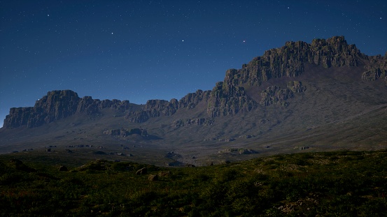 Amid the tranquil night sky, the mountain fields stretch out, creating a serene and captivating scene.
