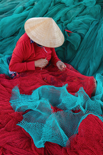 High angle view of fishmen is knitting fishing net on a large beautiful turquoise fishing net Khanh Hoa province, central Vietnam