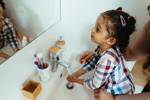 Mother and daughter in bathroom, washing hands and face