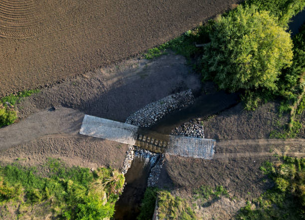 The dirt road leads across a stream that crosses river and continues when the flood road is impassable. restoration of watercourses and relocation upright drainage of fields into meandering The dirt road leads across a stream that crosses river and continues when the flood road is impassable. restoration of watercourses and relocation upright drainage of fields into meandering , river ford, wade impassable limit stock pictures, royalty-free photos & images