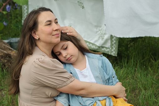 Amidst fluttering laundry, mother and daughter share joyous embrace in the backyard. moment highlights irreplaceable bond between parent and child, foundational to child's emotional development
