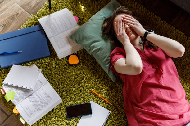 istock Tired student lying ont the floor, rubbing her eyes while tired from studying 1703881566