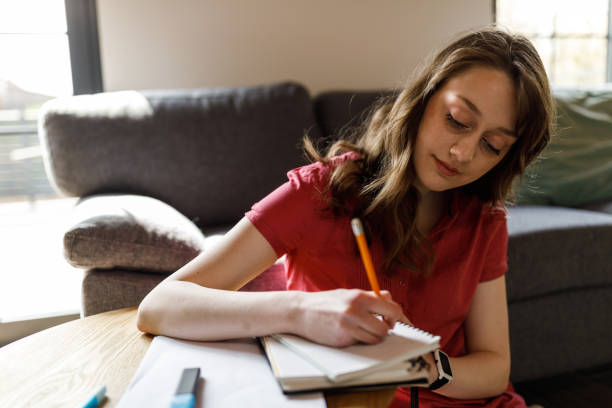 istock Young female university student studying and writing notes in notebook when preparing for exam 1703881572